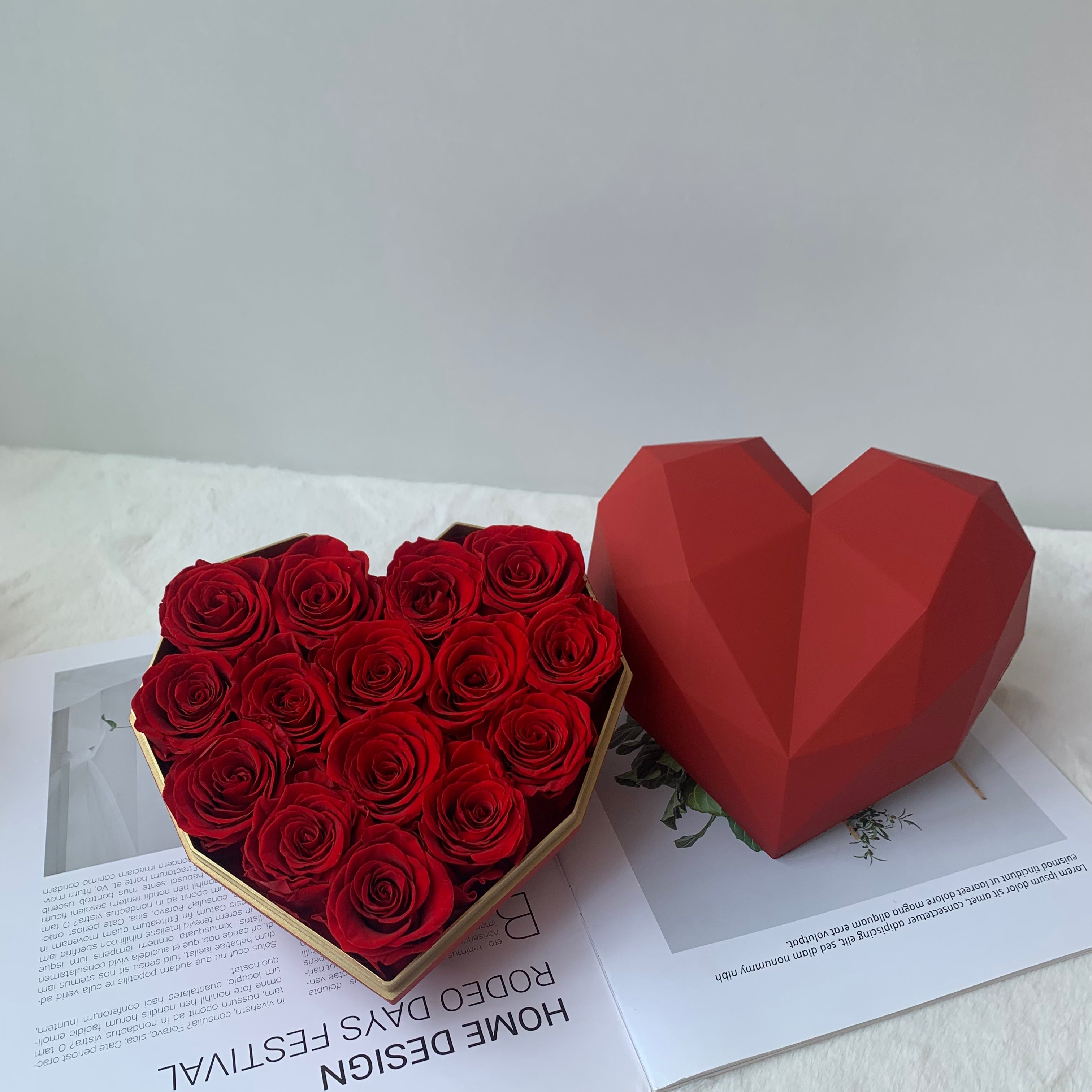 Heart-shaped box filled with red roses on a white surface