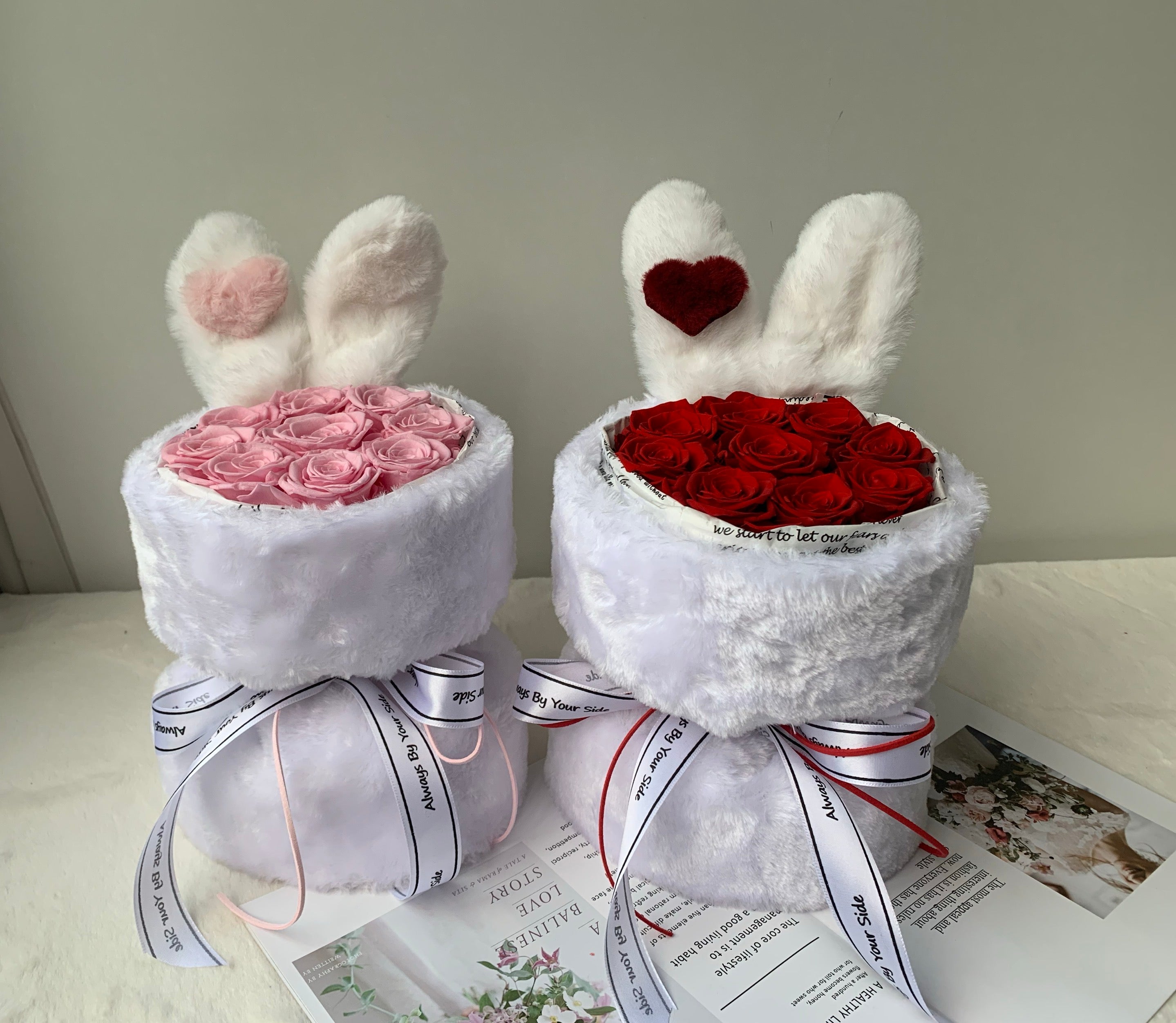 Two white bunny-shaped gift boxes with pink and red roses on a light surface.