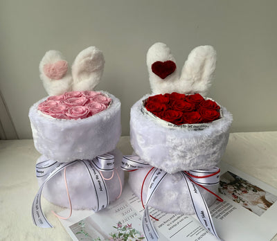 Two white bunny-shaped gift boxes with pink and red roses on a light surface.