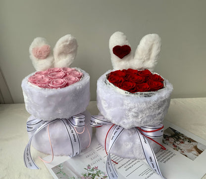 Two white bunny-shaped gift boxes with pink and red roses on a light surface.